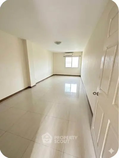 Spacious empty room with large window and tiled flooring, perfect for customization.