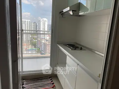 Compact kitchen with modern appliances and balcony view in urban apartment