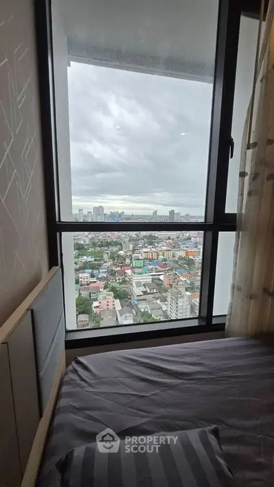 High-rise bedroom with stunning cityscape view through large window.