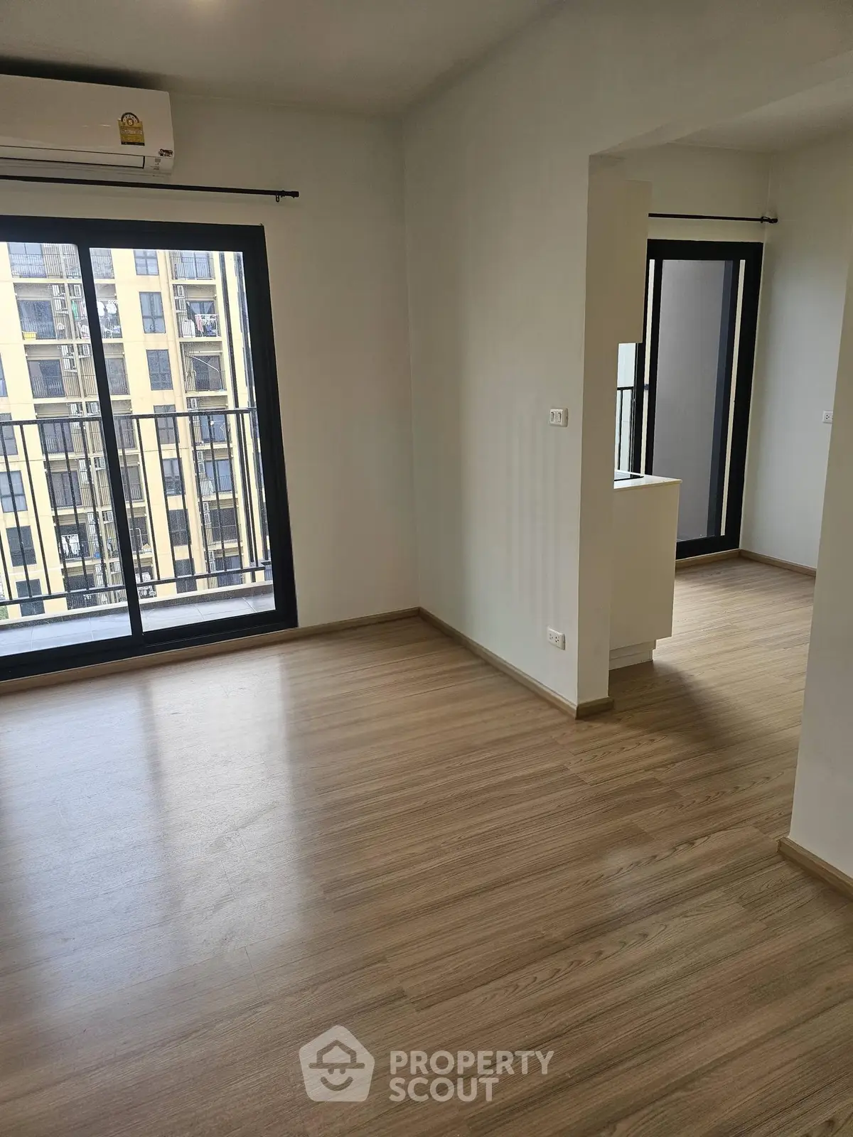 Spacious modern apartment with wooden flooring and large windows offering ample natural light.