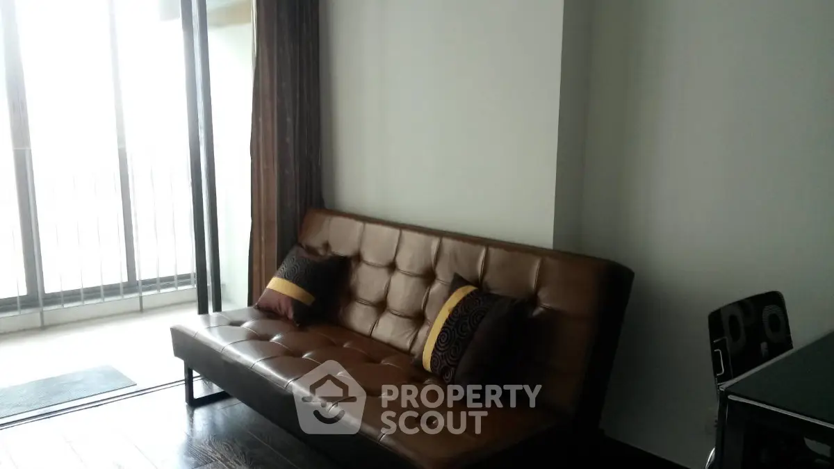 Modern living room with stylish brown leather sofa and balcony view.