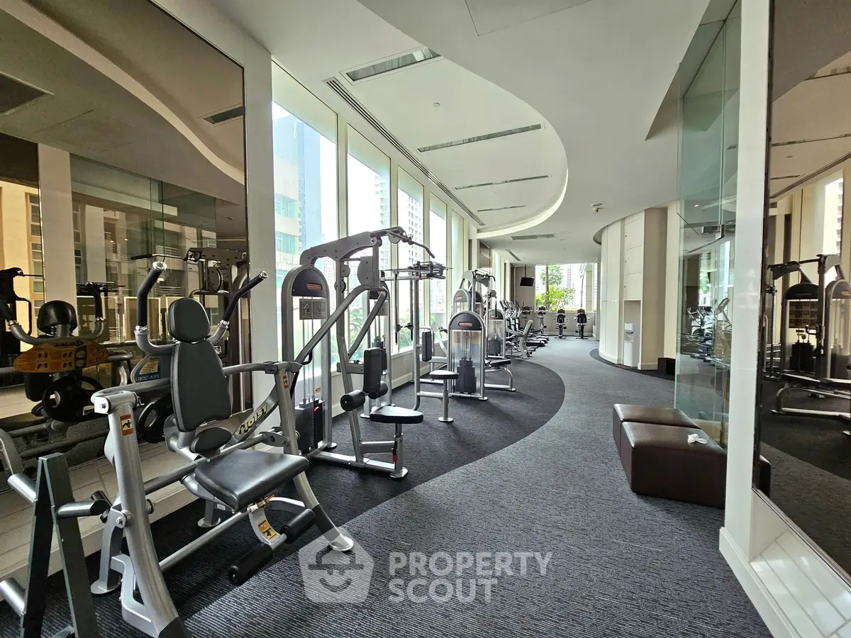 Luxurious gym with modern equipment and panoramic city views in high-end residential building.