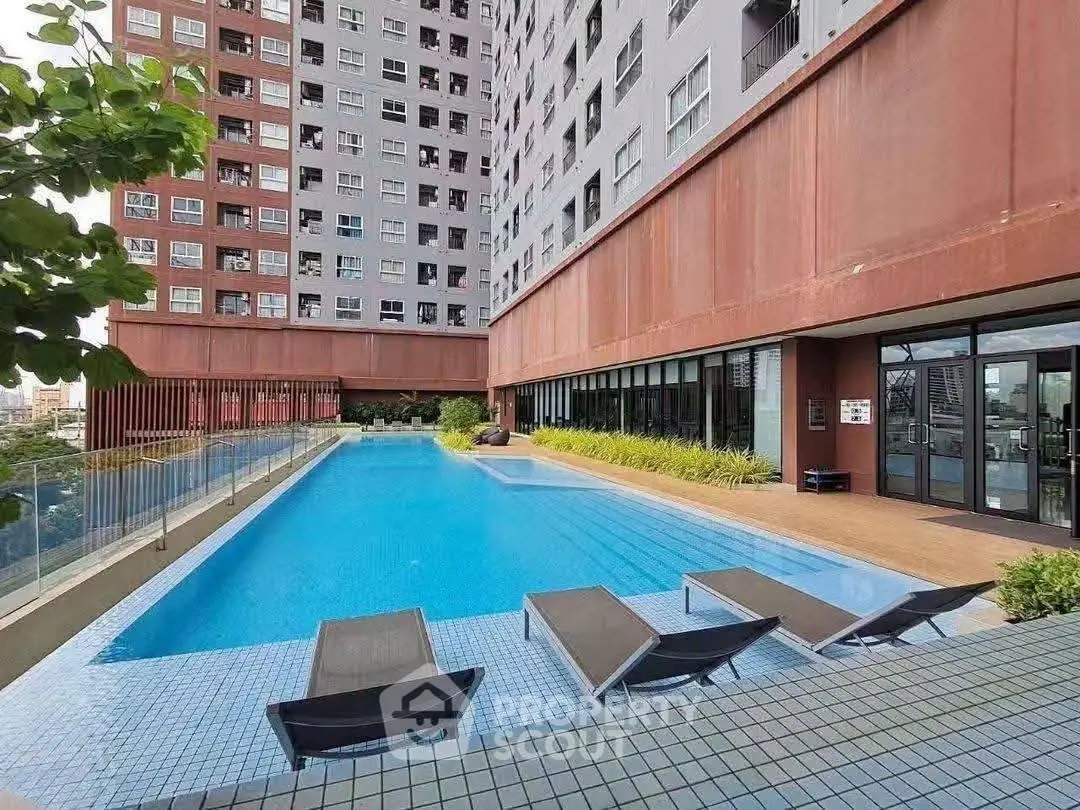 Modern apartment building with a luxurious outdoor pool and sun loungers, perfect for relaxation.