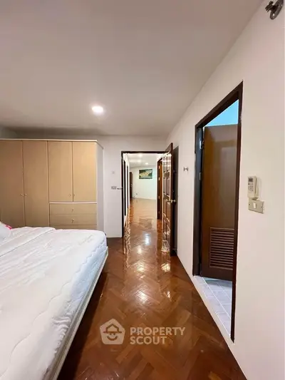 Spacious bedroom with wooden flooring and ample storage in modern apartment.