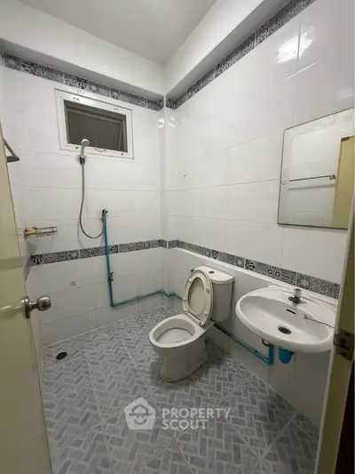 Simple bathroom with white tiles and basic fixtures, ideal for budget-friendly real estate listings.