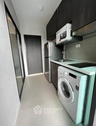 Modern kitchen with washing machine and sleek cabinetry in compact layout.