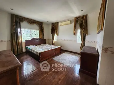Spacious bedroom with elegant curtains and wooden flooring