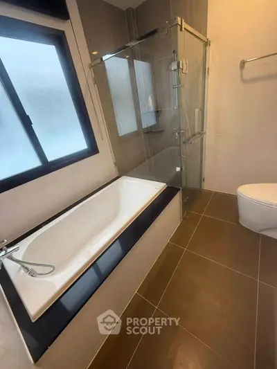 Modern bathroom with bathtub and glass shower enclosure in stylish home.