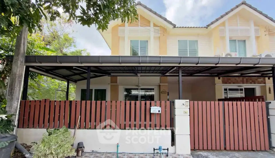 Charming two-story house with covered carport and wooden fence in a serene neighborhood.