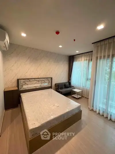 Modern bedroom with large window and stylish decor in a contemporary apartment.