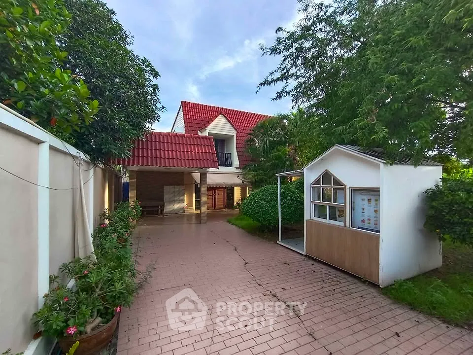 Charming house with red roof, lush garden, and spacious driveway