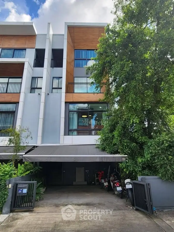 Modern multi-story building with lush greenery and secure gated entrance, ideal for urban living.