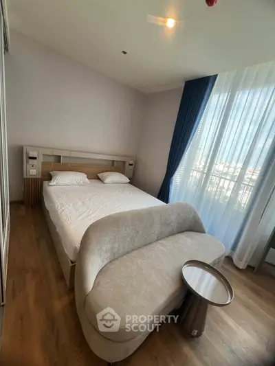 Modern bedroom with stylish furniture and large window offering natural light and city view.