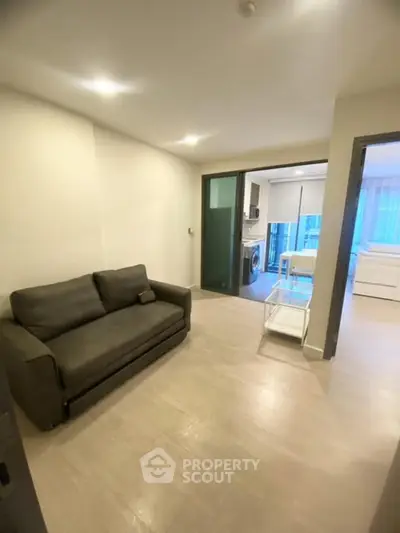Modern apartment interior with cozy living room and open kitchen layout, featuring sleek furniture and bright lighting.