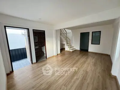 Spacious modern living room with wooden flooring and staircase, ideal for family gatherings.