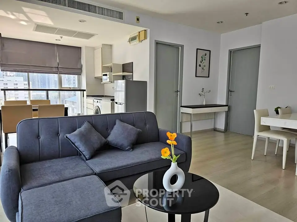 Modern living room with stylish furniture and open kitchen in a high-rise apartment.