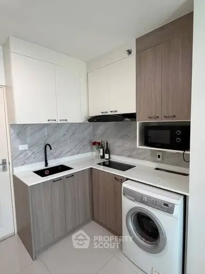 Modern kitchen with sleek cabinetry, built-in microwave, and washing machine in compact layout.