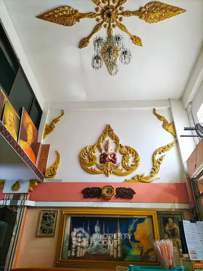 Elegant interior with ornate golden decor and chandelier, showcasing cultural artwork and high ceilings.