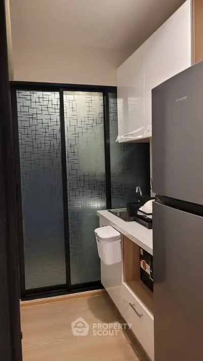 Modern compact kitchen with sleek cabinetry and stainless steel fridge
