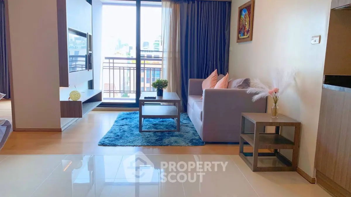 Modern living room with balcony view, stylish decor, and cozy seating area in a bright apartment.