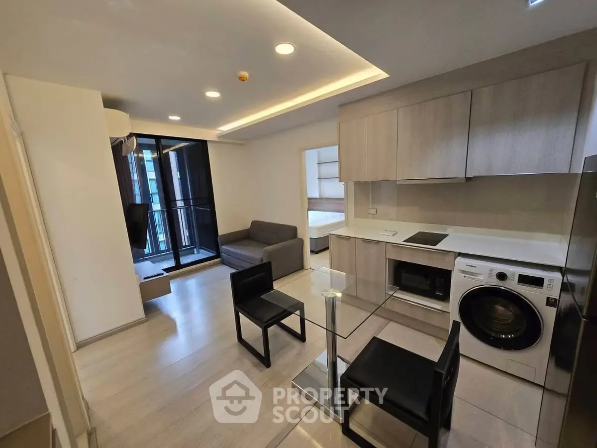 Modern open-plan living room with kitchen, featuring sleek furniture and appliances.