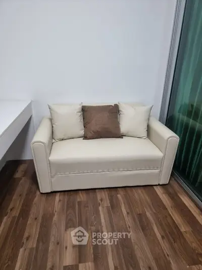 Cozy small sofa in modern living room with wooden flooring and large window.