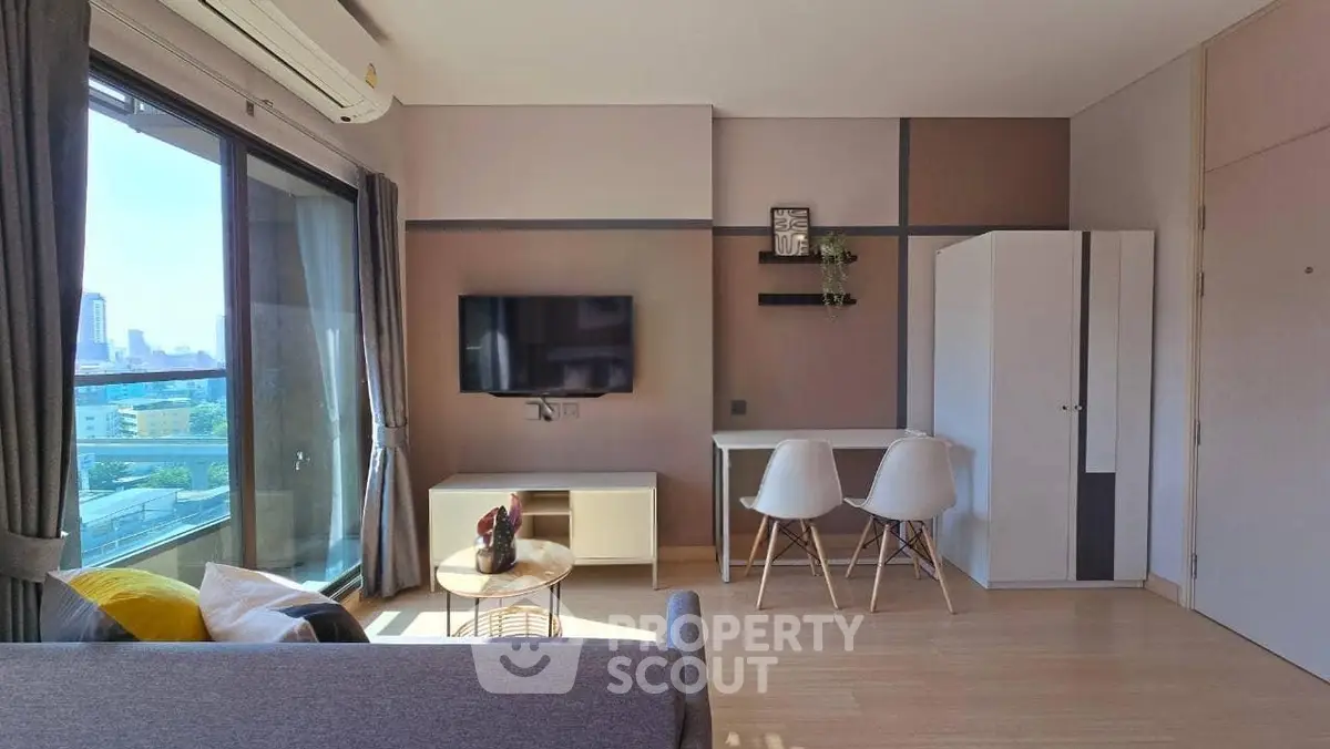 Modern living room with city view, featuring sleek furniture and large windows for natural light.