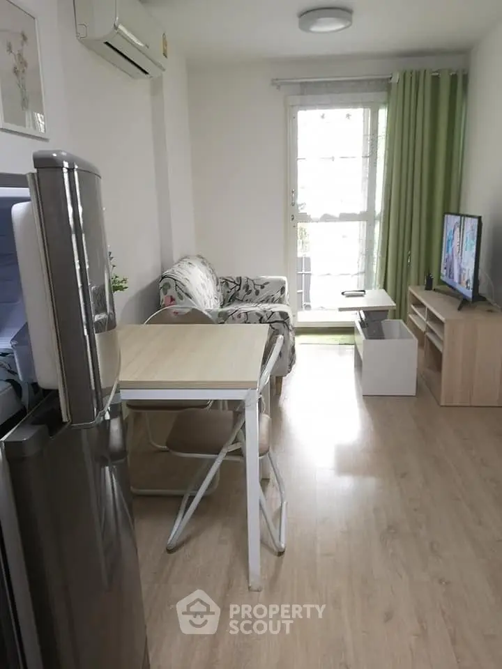 Cozy living room with modern decor and natural light, featuring a compact dining area and TV setup.