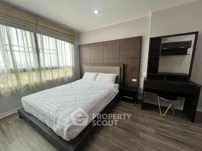 Spacious bedroom with modern furnishings and large window for natural light.