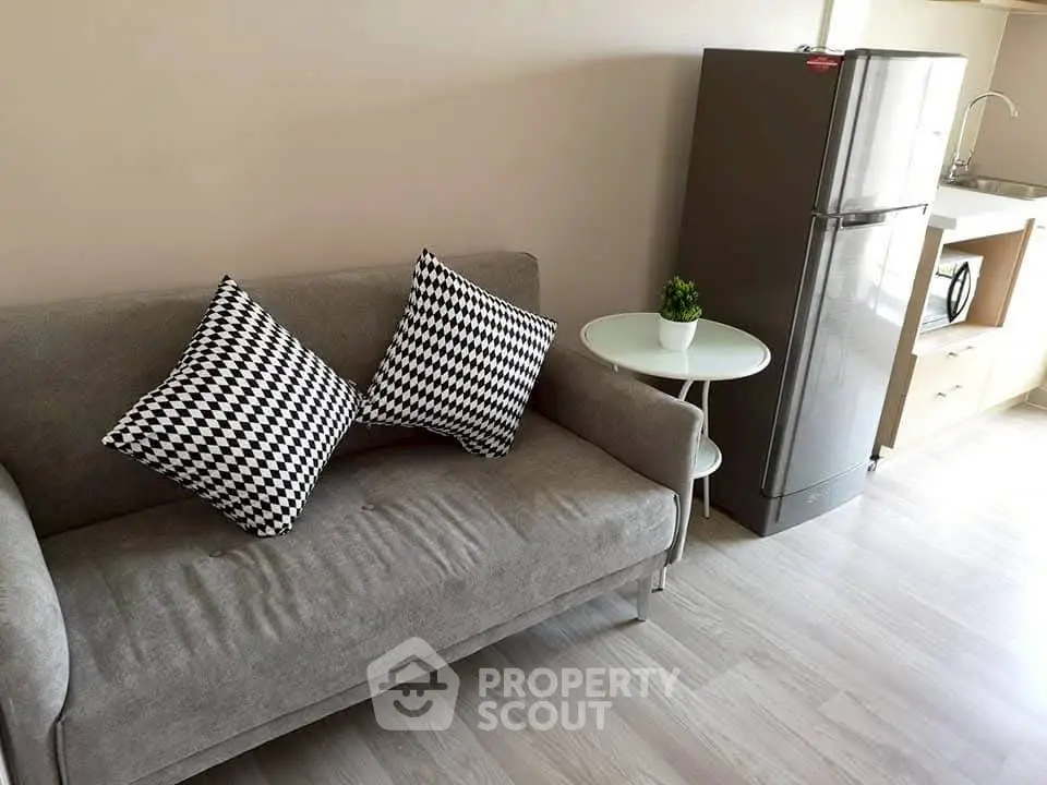 Modern apartment interior with stylish sofa, chic cushions, and sleek kitchen appliances.