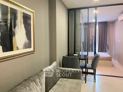 Modern apartment interior with cozy living room and stylish bedroom separated by glass partition.