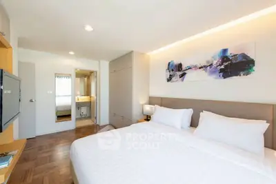 Modern bedroom with stylish decor and ensuite bathroom, featuring a cozy bed and contemporary artwork.