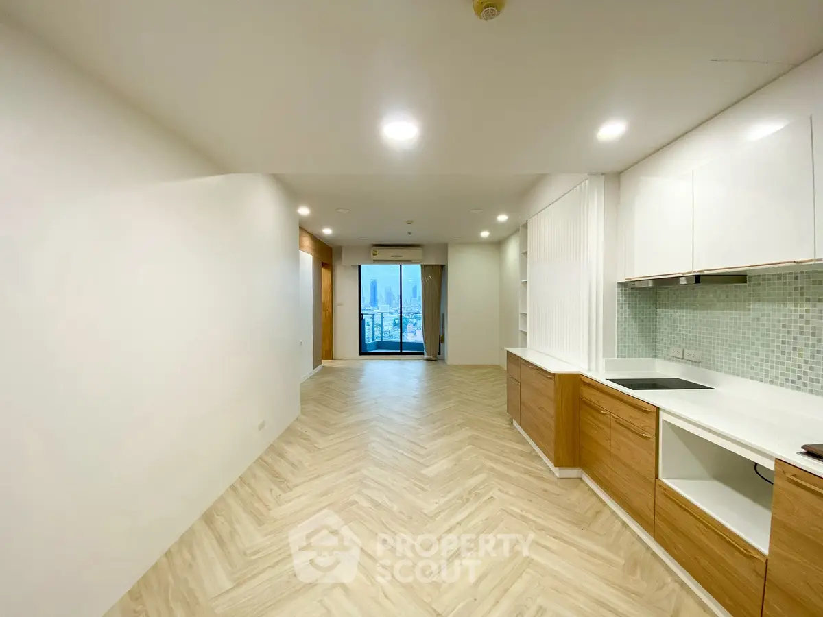 Spacious modern living room with open kitchen and city view balcony in luxury apartment.