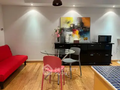 Modern living room with vibrant red sofa, glass dining table, and colorful abstract art on the wall.