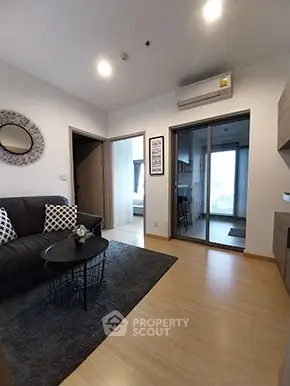 Modern living room with stylish decor and open layout leading to kitchen and bedroom.