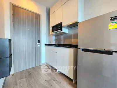Modern compact kitchen with sleek appliances and wooden flooring in a stylish apartment.