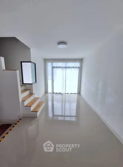 Bright minimalist interior with staircase and large window, perfect for modern living.