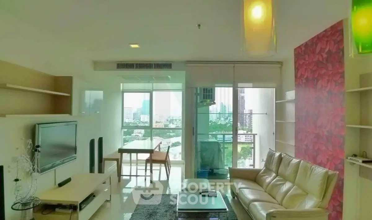 Modern living room with city view, stylish decor, and ample natural light in a high-rise apartment.