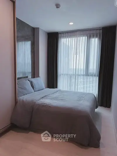 Cozy bedroom with large window and modern decor in a stylish apartment.