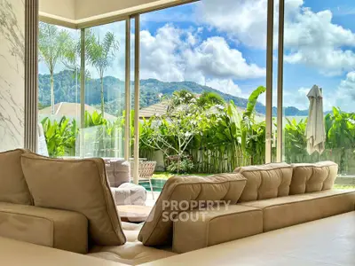 Luxurious living room with panoramic garden and mountain view, featuring plush seating and floor-to-ceiling windows.