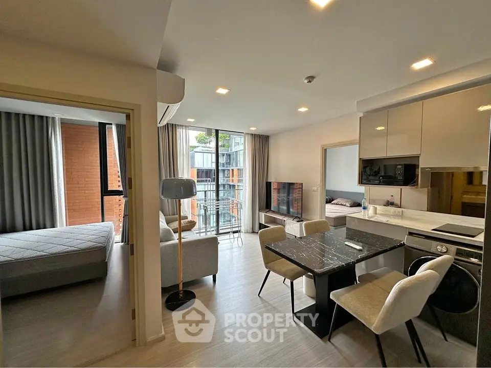 Modern open-plan living room with dining area and balcony access in stylish apartment.