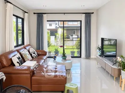 Spacious living room with modern leather sofa and large windows overlooking garden.