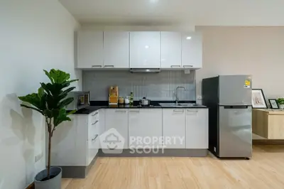 Modern kitchen with sleek white cabinets and stainless steel fridge in a stylish apartment.