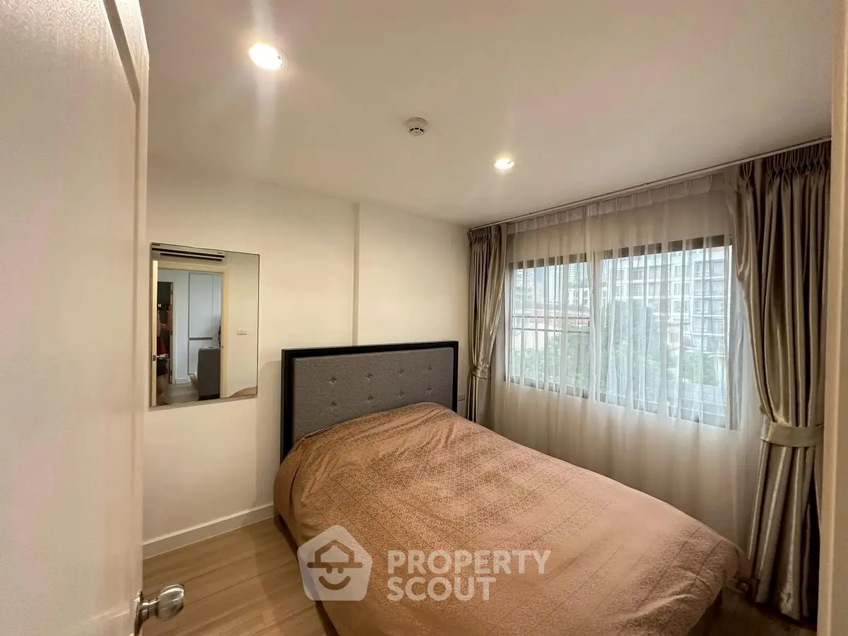 Cozy bedroom with large window and modern decor in a stylish apartment.
