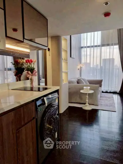 Modern open-layout living room with city view, featuring sleek kitchen and cozy seating area.