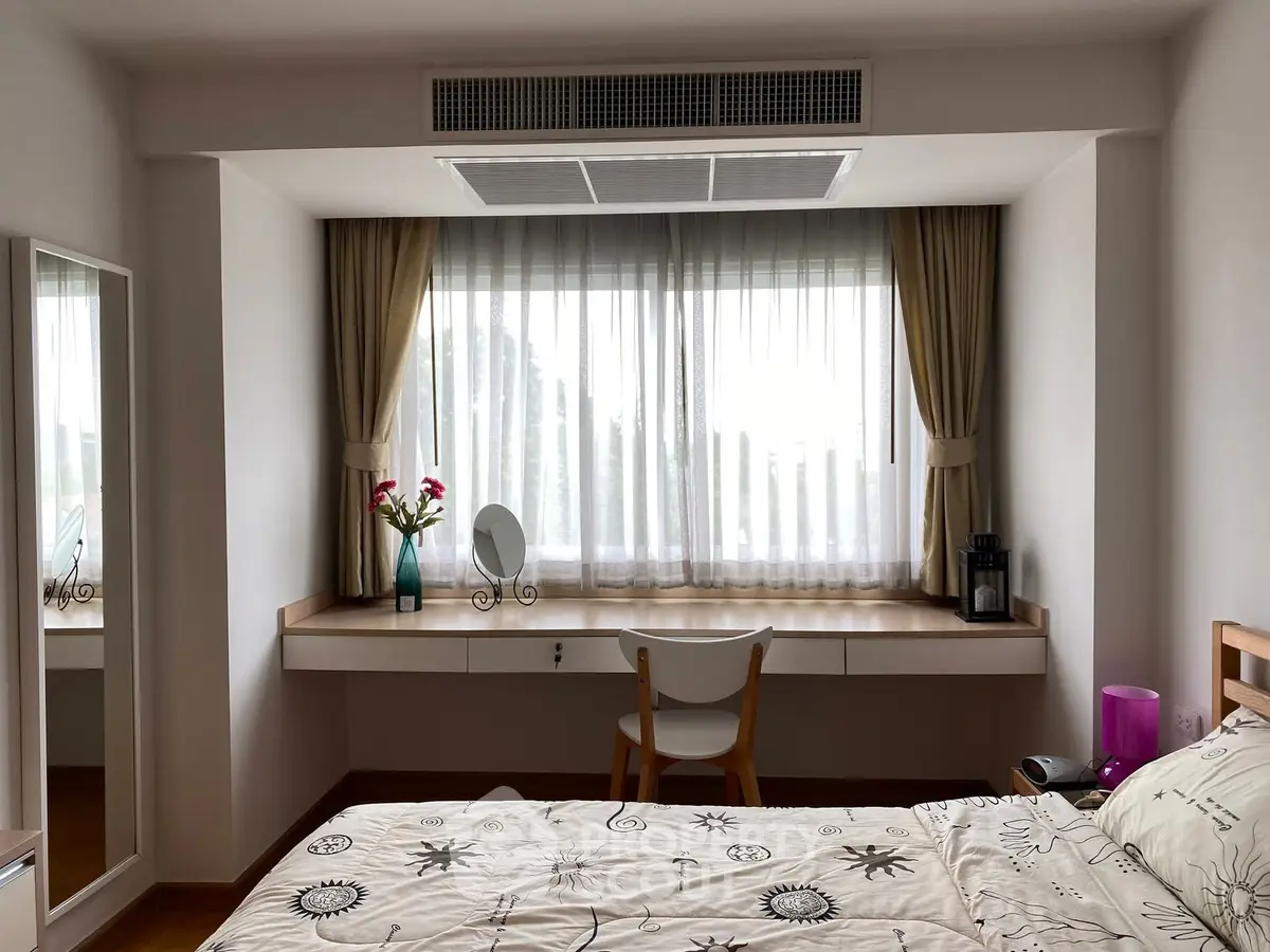 Charming bedroom with large window, elegant curtains, and cozy decor, perfect for relaxation and comfort.