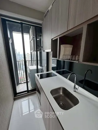 Modern kitchen with sleek cabinetry and city view from balcony, featuring a compact yet functional design.