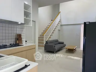 Modern open-plan living room with sleek kitchen and stylish staircase