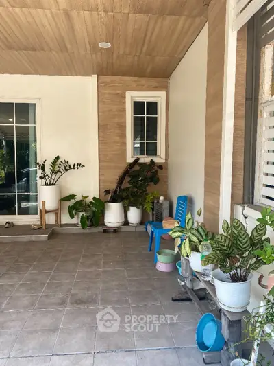 Charming home entrance with potted plants and cozy seating area