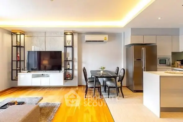 Modern open-plan living room with sleek kitchen and dining area, featuring hardwood floors and stylish decor.